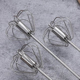 three metal whisks are on a gray surface next to a bowl