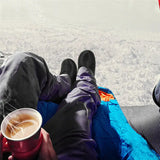 a person laying on a blanket with a cup of coffee