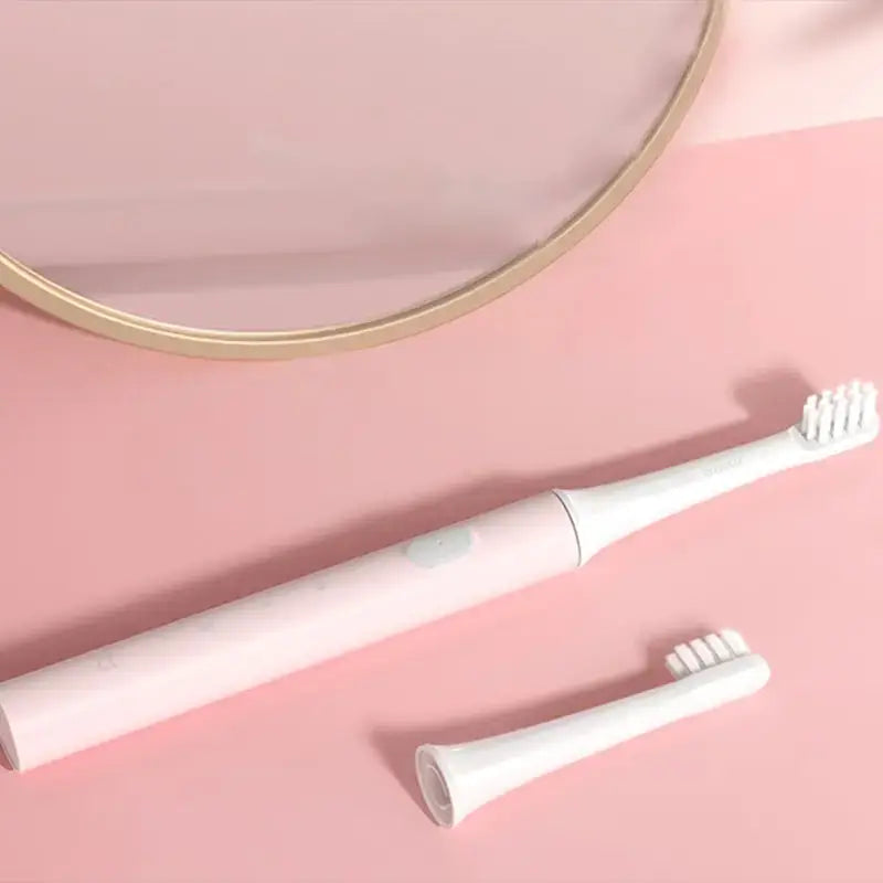 a toothbrush and a mirror on a pink background