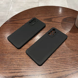 Two black smartphone cases with camera cutouts on a wooden surface.