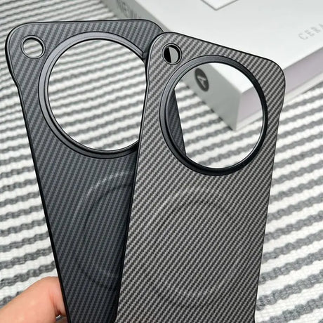 Two carbon fiber phone cases with circular camera cutouts.