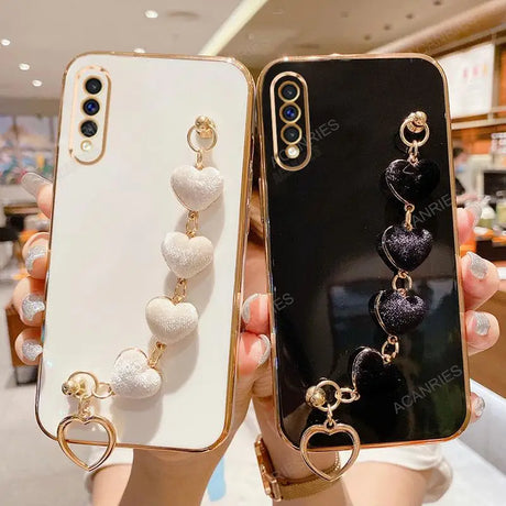 Two decorative smartphone cases with dangling heart-shaped charms attached.