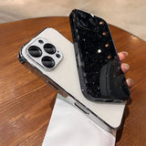 Two glitter-finish iPhone cases, one white with a silver camera bezel, and one black with scattered light reflections.