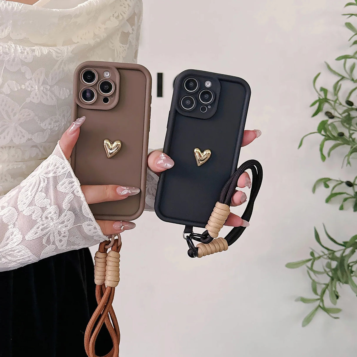 Two heart-adorned phone cases with wrist straps.