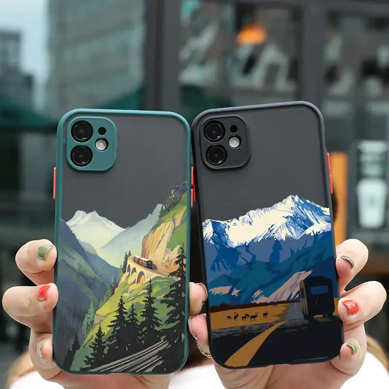 two iphone cases with mountains and trees on them
