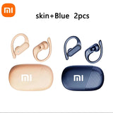 Two pairs of wireless earbuds with ear hooks and charging cases, one in a skin/beige color and the other in blue.