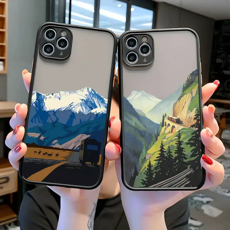 two people holding up their iphone cases with mountains in the background