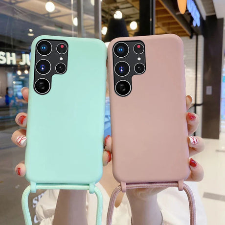 Two silicone phone cases with camera cutouts and attached lanyards, one in mint green and one in pink.