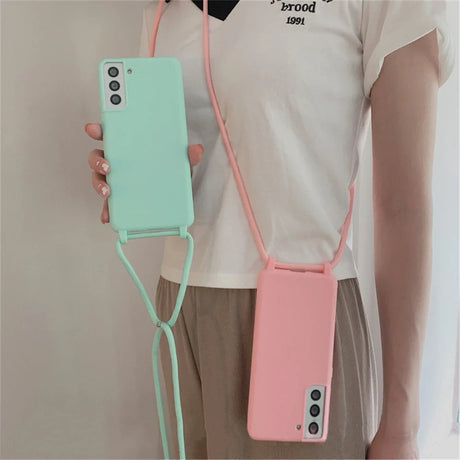 Two silicone smartphone cases with attached lanyards, one mint green and one pink.