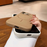 Two smartphone cases in beige and white, one with a visible charging port and speaker holes, and the other with camera cutouts and a circular magnetic charging design.