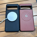 Two smartphone cases, one black with a white circular charger and one burgundy with a Google ’G’ logo.