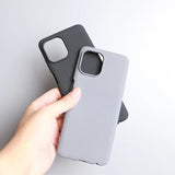 Two smartphone cases, one black and one light gray, held in a hand.