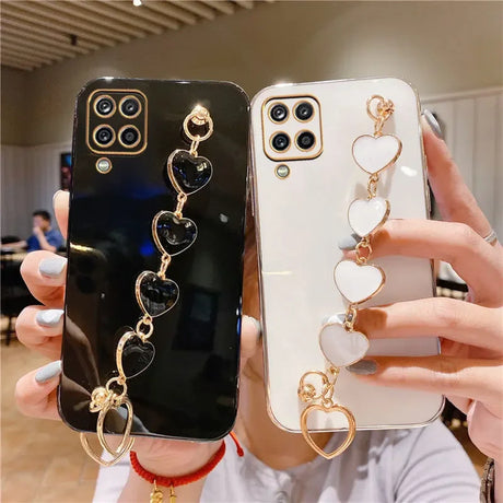 Two smartphone cases with decorative heart-shaped charms attached.