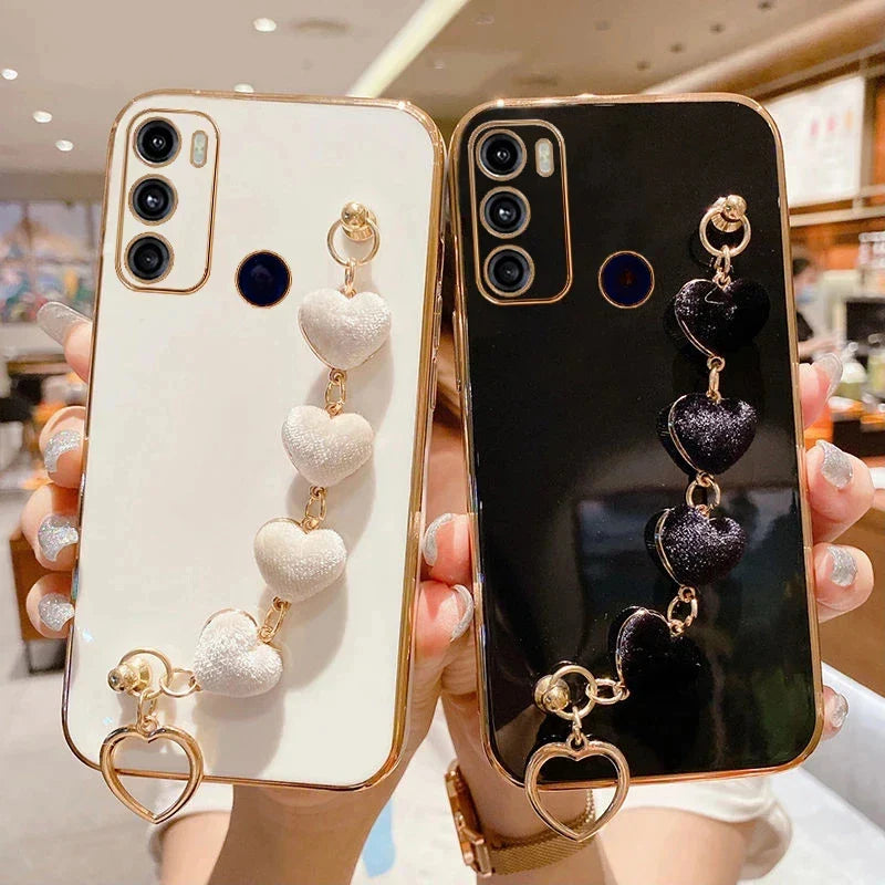 Two smartphone cases with decorative heart-shaped charms attached.