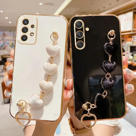 Two smartphone cases with decorative heart-shaped charms attached.