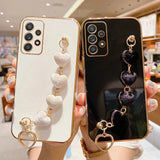 Two smartphone cases with decorative heart-shaped charms attached.