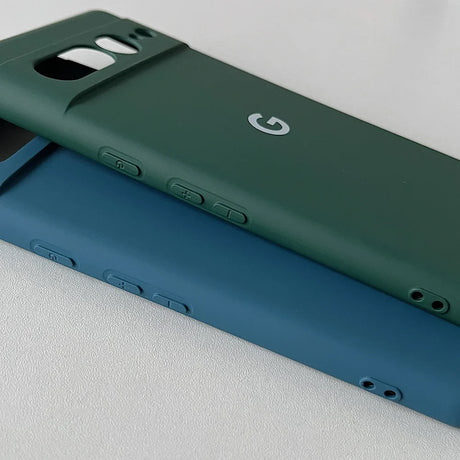 Two smartphone cases, one green and one blue, with the Google ’G’ logo visible on the green case.