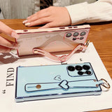 Two smartphone cases with heart-shaped strap holders.
