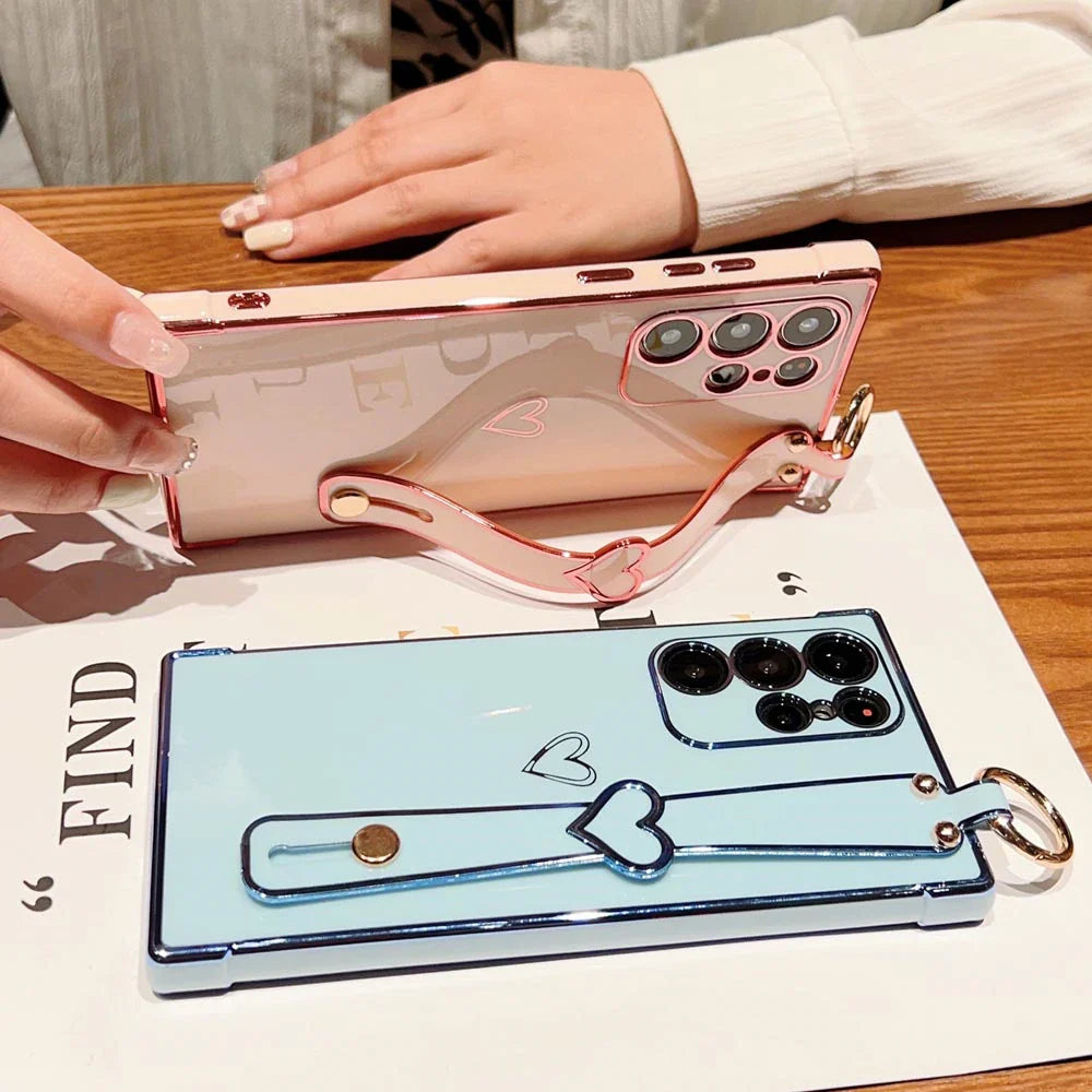 Two smartphone cases with heart-shaped strap holders.