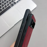 Two smartphones in protective cases, one with a carbon fiber pattern and the other with a red woven texture and a camera bar.