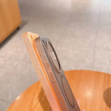 Two translucent phone cases, one peach and one grey, with visible MagSafe rings and side buttons.