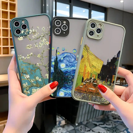 Two women holding up their iphone cases with a painting on them