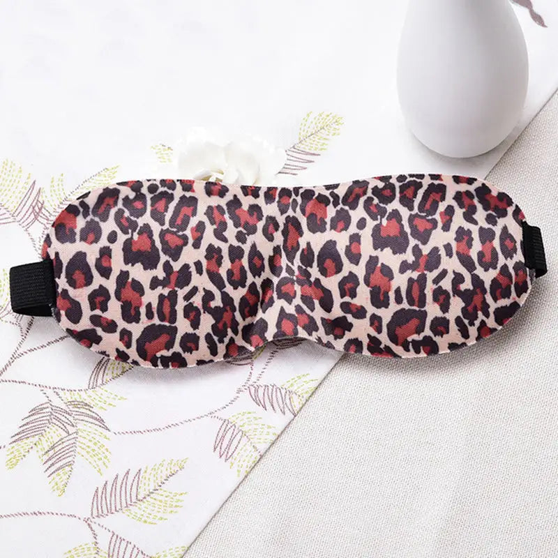 a pink and black leopard print eye mask with a black eye patch