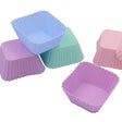 four different colored cupcake cases are lined up on a white surface
