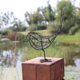 a metal bird sculpture on a wooden post