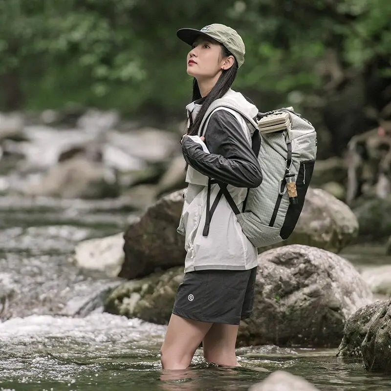 a woman standing in a river with a backpack