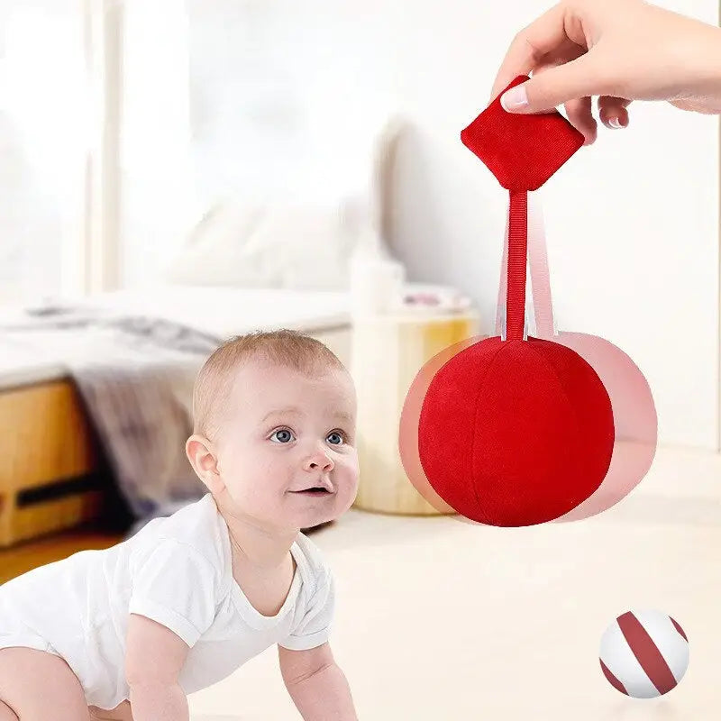 a baby crawling on the floor with a red ball