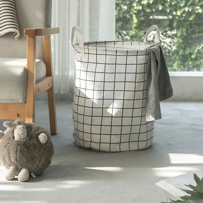 a white and black basket sitting on the floor next to a chair