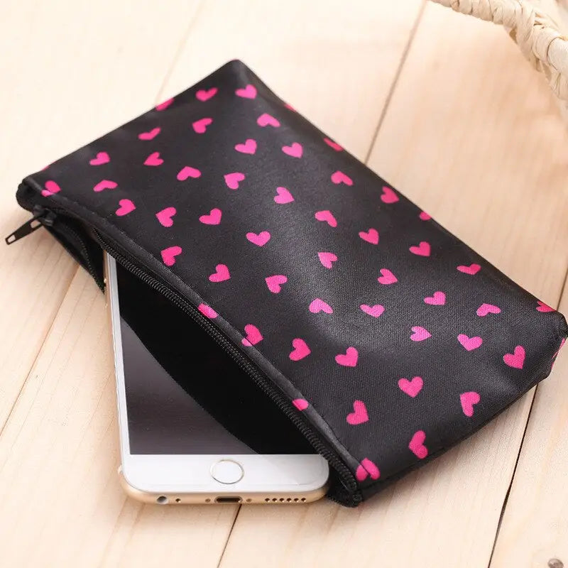 a black phone case with pink hearts on it