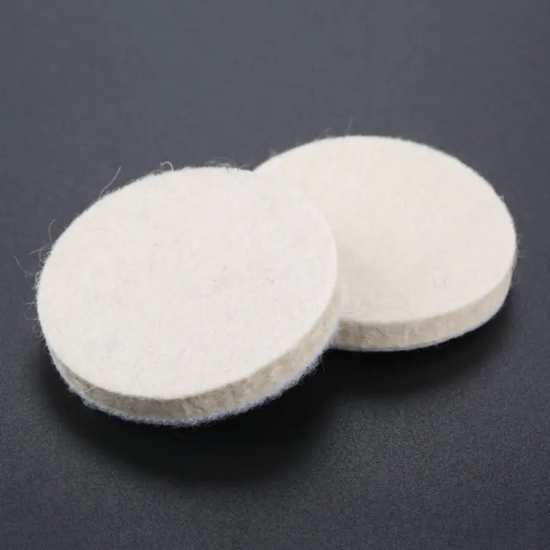 two white round felt pads on a black background