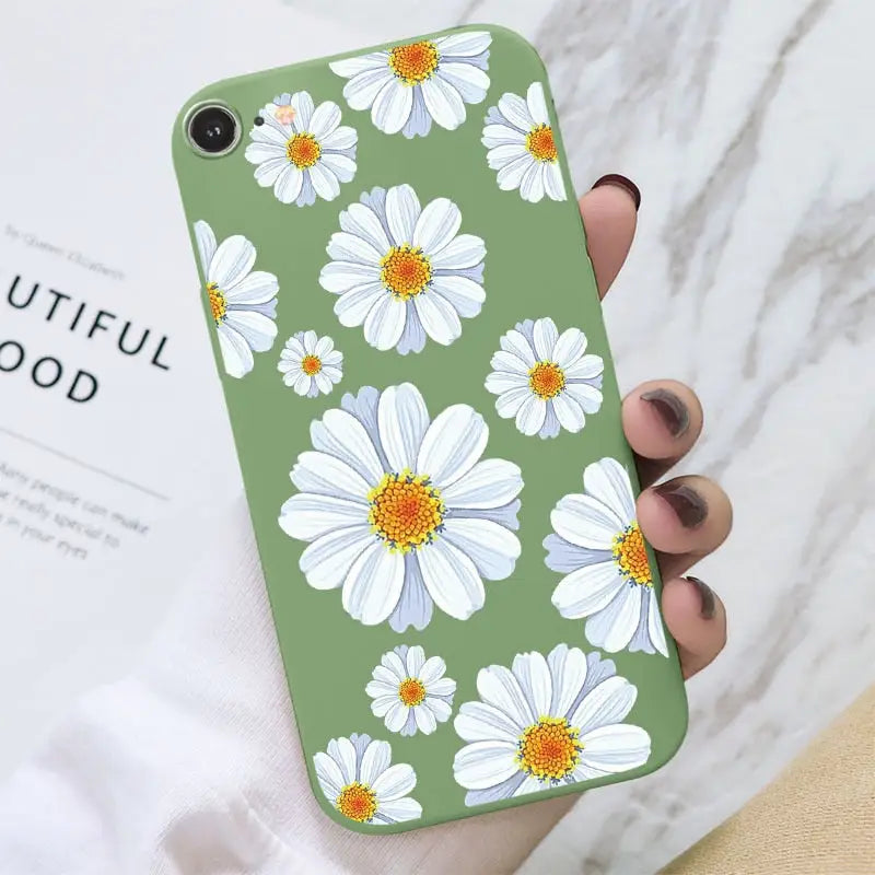 a woman holding a green phone case with white flowers
