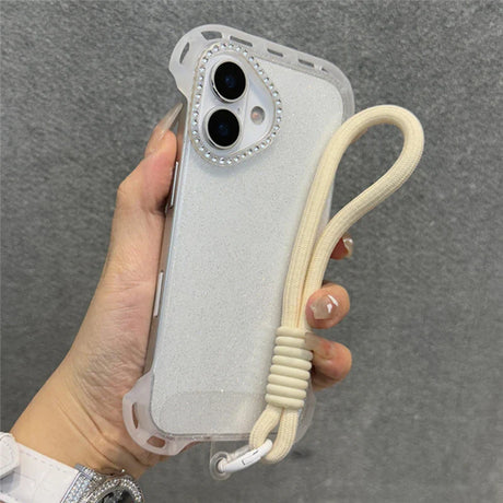 A white glitter phone case with a rhinestone camera bezel and an attached cream-colored wrist lanyard.