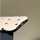 the back of a white iphone case with black polka dots