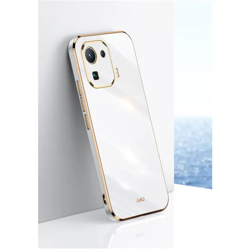 the back of a white iphone case with gold trim