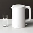 A white kettle with a glass of water