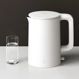 a white kettle with a glass of water