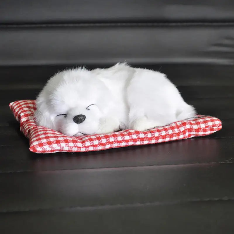 a white puppy is sleeping on a red and white checkered blanket