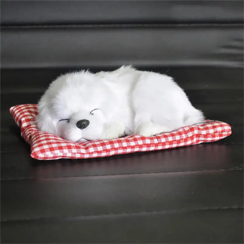 a white puppy sleeping on a red and white checkered blanket