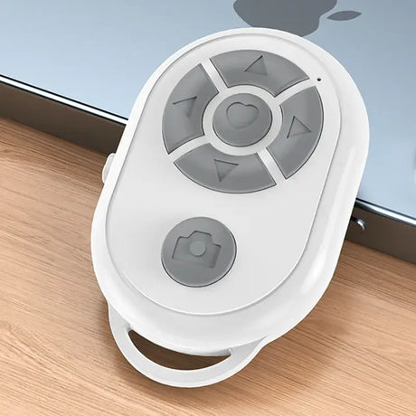 A white remote control device on a wooden floor