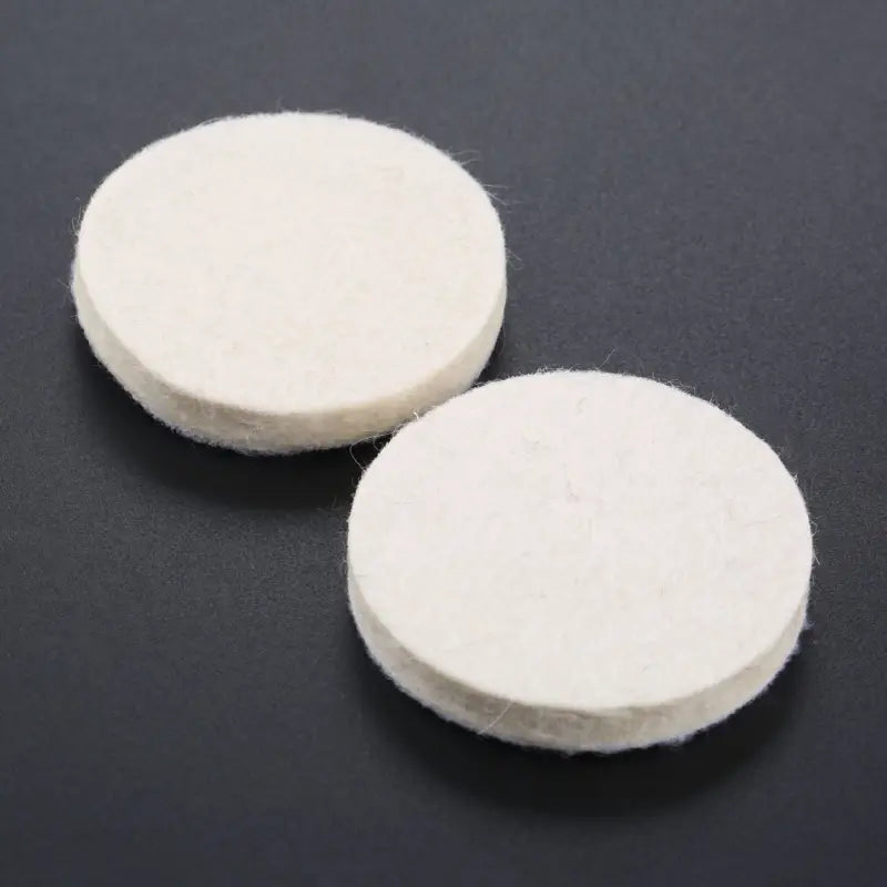 two white round felt pads on a black surface