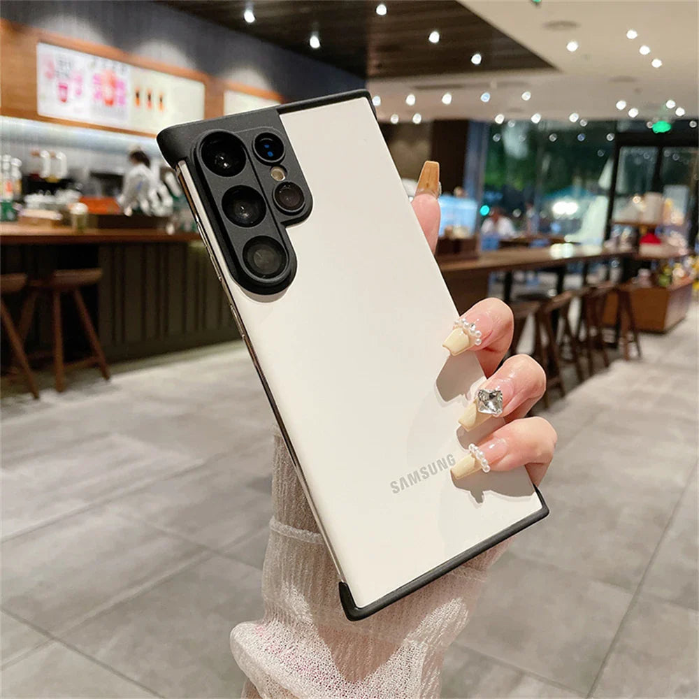 White Samsung smartphone with a black camera module and a black protective case, held by a hand with jeweled nails.