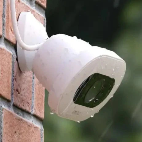 a white security camera mounted on a brick wall