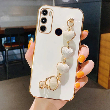 White smartphone with a gold-trimmed case and a decorative heart-shaped charm attached.