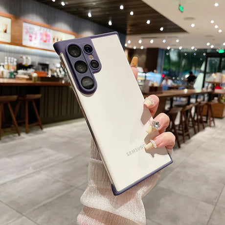 White smartphone with a purple camera module and border, held by a hand with decorated fingernails.