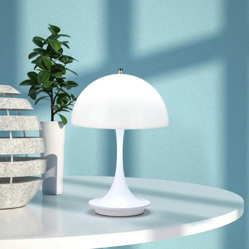 A white table with a lamp and a plant