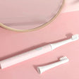 A white toothbrush and a pink background